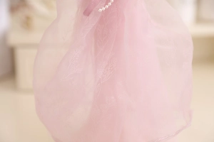 Close-up of pink organza jewelry stand with white floral embroidery and pearl accents