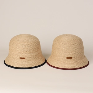 Dettaglio di cappelli in rafia con etichette in pelle fatte a mano e bordi colorati