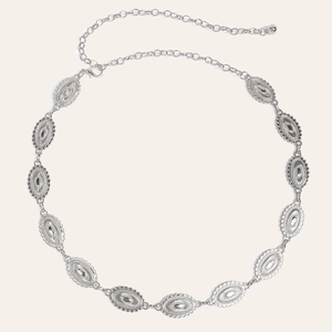 Detailed view of silver ethnic style metal waist belt with carved oval plates and clasp