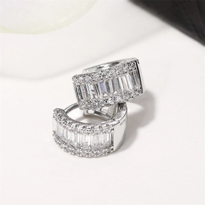 Macro shot of silver baguette-cut zircon huggie earrings with detailed micro-pave setting