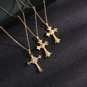 Three gold cross necklaces with colorful gemstones on a black textured background