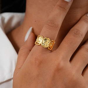 Gros plan d'une bague fleur géométrique dorée avec texture martelée sur le doigt