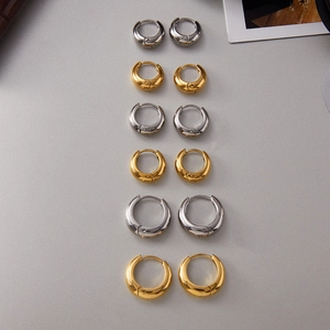 Varie dimensioni di orecchini a cerchio cicciotti in oro e argento su fondo grigio