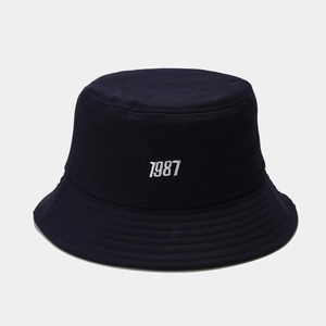 Close-up of 1987 white embroidery on a navy blue cotton bucket hat with stitched brim