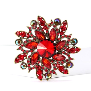 Close-up of vintage flower brooch with red crystals and bronze metal base on white background