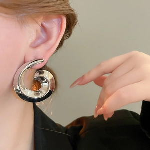 Macro detail of large silver snail spiral earring worn by model with metallic mirror finish