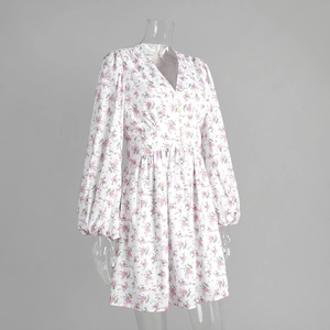 Detail of floral print V-neckline with decorative buttons on a white mini dress