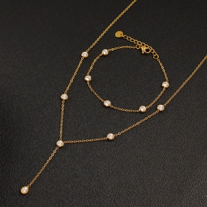 Elegant gold-plated necklace and bracelet set with round cubic zirconia on black background