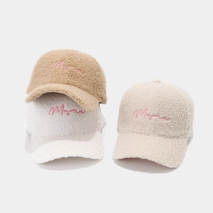 Dettaglio del ricamo Mama su cappellini in pile nei colori kaki, bianco e beige