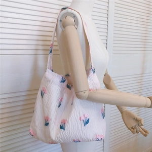Détail d'un sac cabas rose à fleurs en tissu gaufré sur l'épaule d'un mannequin