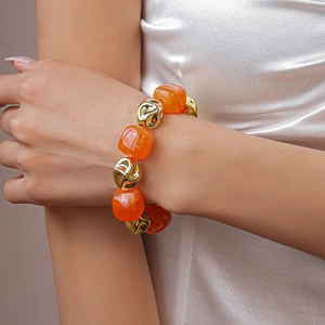Macro detail of irregular orange acrylic beads and gold accents on a beaded necklace
