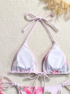 Detail of floral bikini top with neck ties and size label on woven beach background