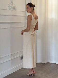 Détails du dos croisé et de l'ourlet basque sur l'ensemble jupe et haut beige en lin
