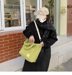 Woman in black coat carrying a fuzzy avocado green sherpa tote bag outdoors