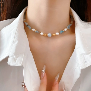 Close-up of freshwater pearl and aquamarine beaded necklace worn on a female neck