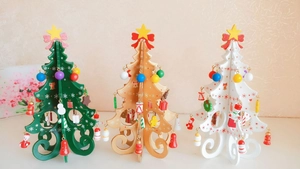 Detailed view of three mini wooden Christmas trees in green, gold, and white with ornaments