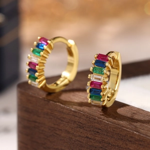Macro shot of 925 silver gold-plated hoop earrings with colorful baguette-cut zircons