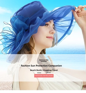Detail of royal blue organza sun hat with oversized flower and wavy wide brim on a beach