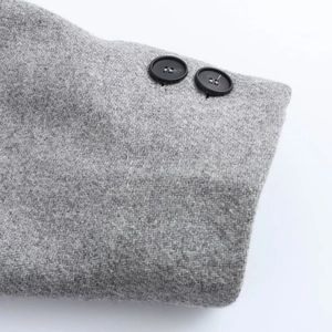 Close-up of grey wool coat sleeve with two matte black round buttons and woven texture