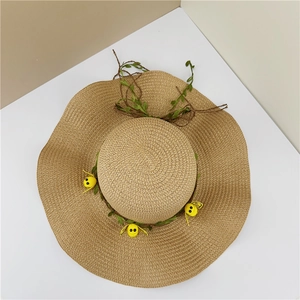 Détail d'un chapeau de paille à bord ondulé avec de jolis ornements d'abeilles jaunes