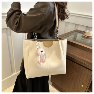 Dettaglio della grande borsa tote bianca con tracolla a catena e ciondolo di peluche rosa