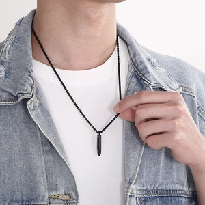 Close-up of black bullet pendant necklace in polished titanium steel on model