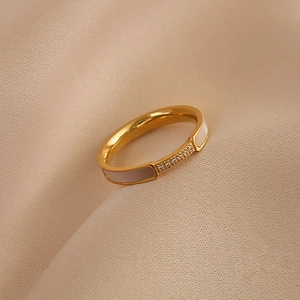 Rose gold titanium ring with white shell inlay and pavé zircon set on beige silk fabric