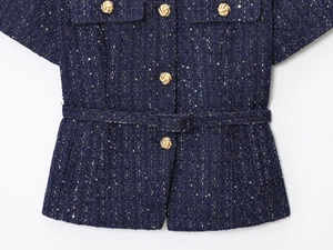 Dettaglio giacca in tweed blu scuro con bottoni dorati a spirale e cintura tessuta