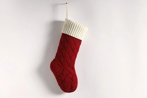 Close-up of a red knitted Christmas stocking with white folded cuff on white background