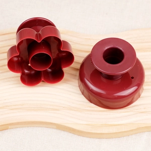 Detail view of dark red flower shaped donut cutter and press tool on wooden board