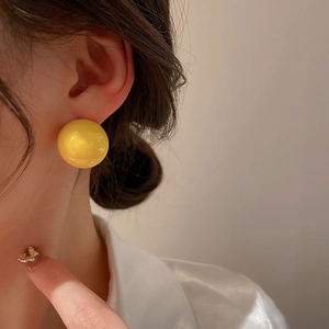 Minimalist bright yellow acrylic sphere stud earrings shown on model for a trendy look