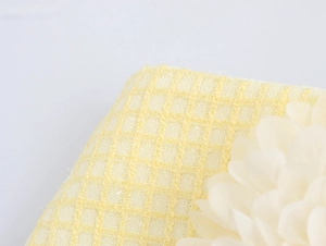 Dettaglio ravvicinato del tessuto tweed a quadri gialli con decorazione floreale 3D