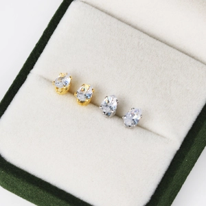 Close-up of gold and silver teardrop zircon stud earrings in a premium jewelry box