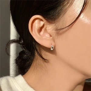 Close-up model wearing minimalist silver oval hoop earrings in 925 sterling silver
