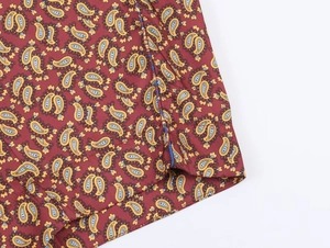Macro d'imprimé paisley sur tissu tissé rouge foncé avec détails de couture d'ourlet