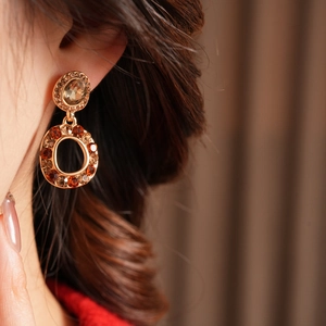 Close-up of vintage gold earrings with amber crystals and hollow circular design