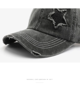 Detail of dark grey washed denim baseball cap with distressed star patch and white stitching