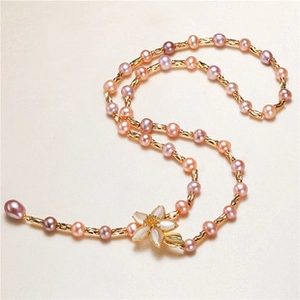 Detail of pink and purple pearl necklace with a white five-petal flower pendant