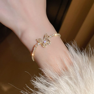 Close-up of gold butterfly bracelet with zircon inlay worn on wrist for an elegant look