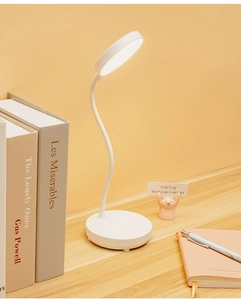 Detail of white LED desk lamp with flexible neck on a wooden desk in a cozy room