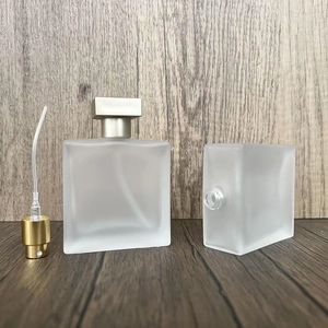 Detail view of square frosted glass perfume bottles with metallic gold spray nozzle