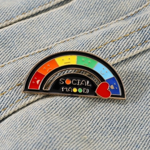 Macro view of Social Mood rainbow enamel pin with sliding heart pointer on denim fabric