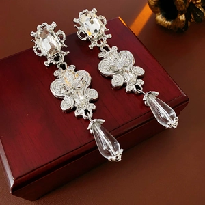 Close-up of vintage resin flower drop earrings with crystals on a wooden jewelry box