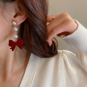 Detailed view of long tassel earrings with white pearls and a red flocked bowknot