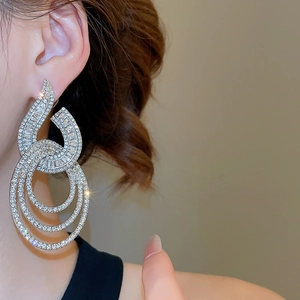 Detail of tiered geometric dangle earrings with silver plating and pavé cubic zirconia