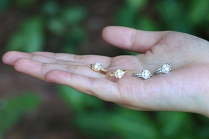 Close-up of gold and silver heart earrings with six-prong set clear zircon crystals