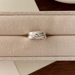 Minimalist 925 sterling silver chunky wave rings set on a beige textured jewelry box