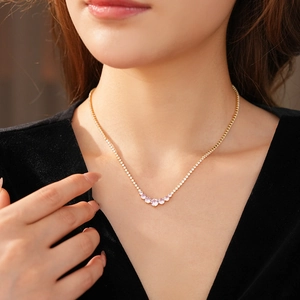 Close-up of a gold necklace with sparkling zircons and a gradient pink-purple pendant