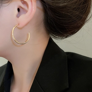 Close-up of a minimalist 18K gold-plated C-shaped hoop earring worn by a model