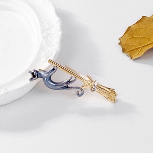 Détail d'une broche chat d'Halloween en émail bleu sur un balai doré strassé